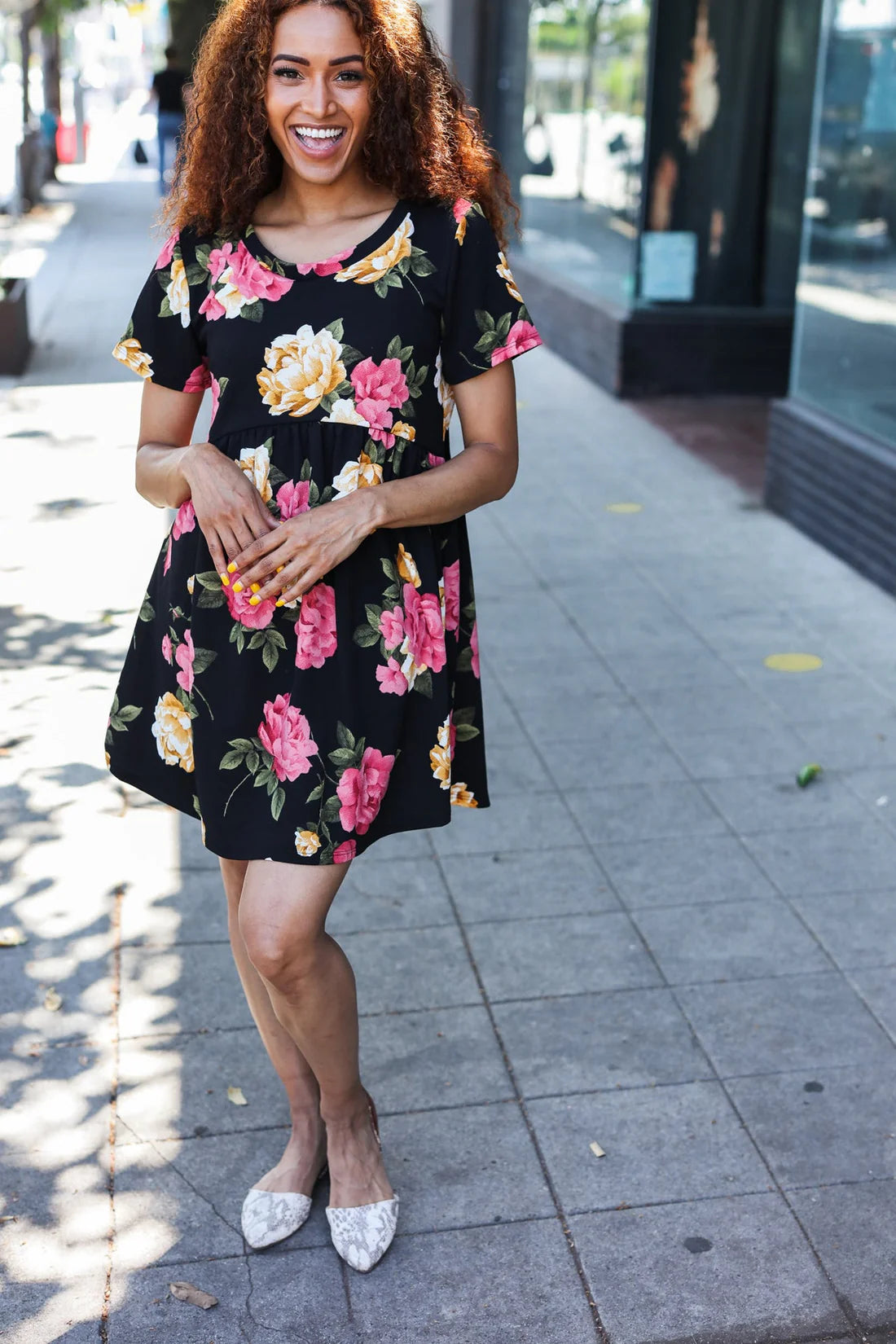 Woman in floral Twilight Garden Party Dress, styled with a black backdrop adorned with colorful blooms.