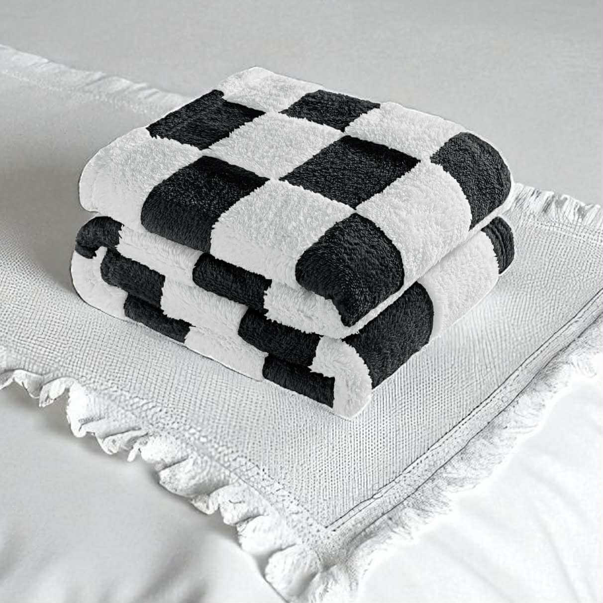 Stylish black-and-white checkerboard NAP CHECK THROW BLANKET stacked on a cozy bedspread for a chic home decor.
