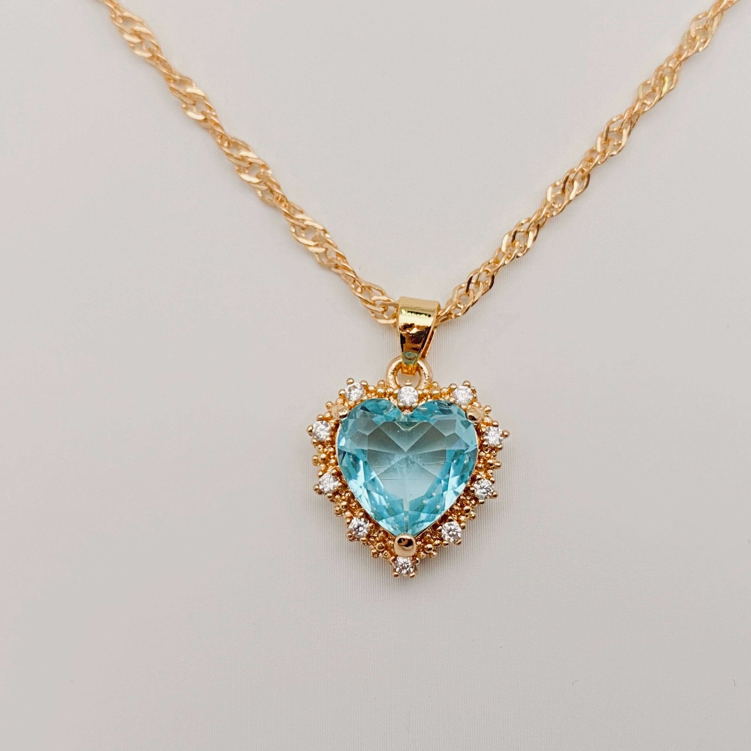 Heart-shaped Pendant Necklace Inlaid Cubic Zirconium with a blue cubic zirconia center and gold chain.