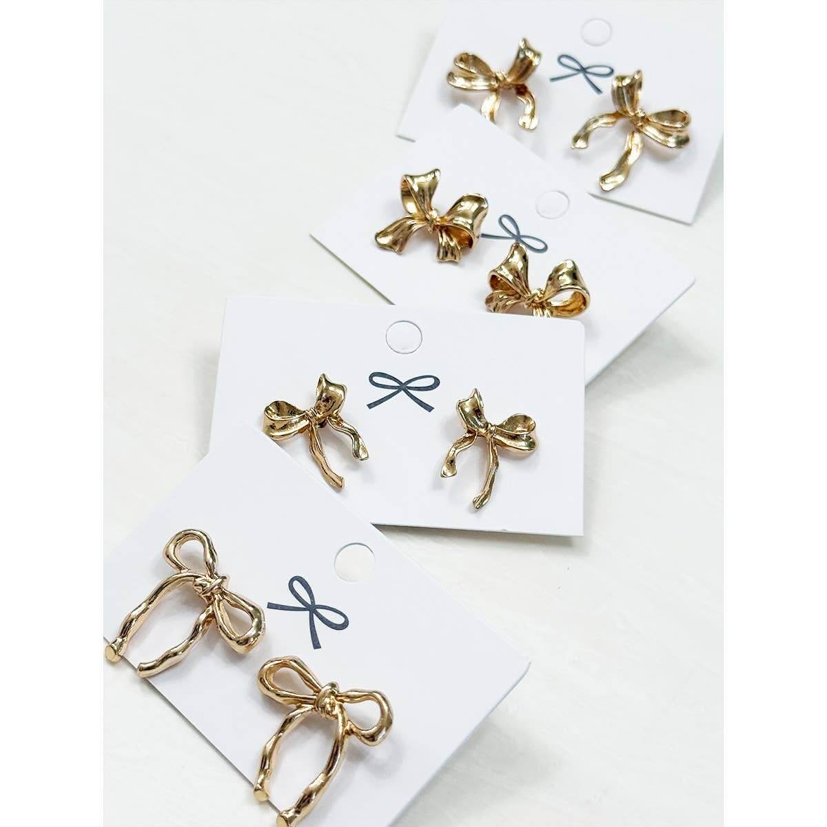 Bows Before Beaus gold bow earrings in four styles displayed on cards.