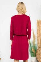 Back view of the Wine and Dine Dress featuring 3/4 sleeves and a cinched waist in a vibrant red color.