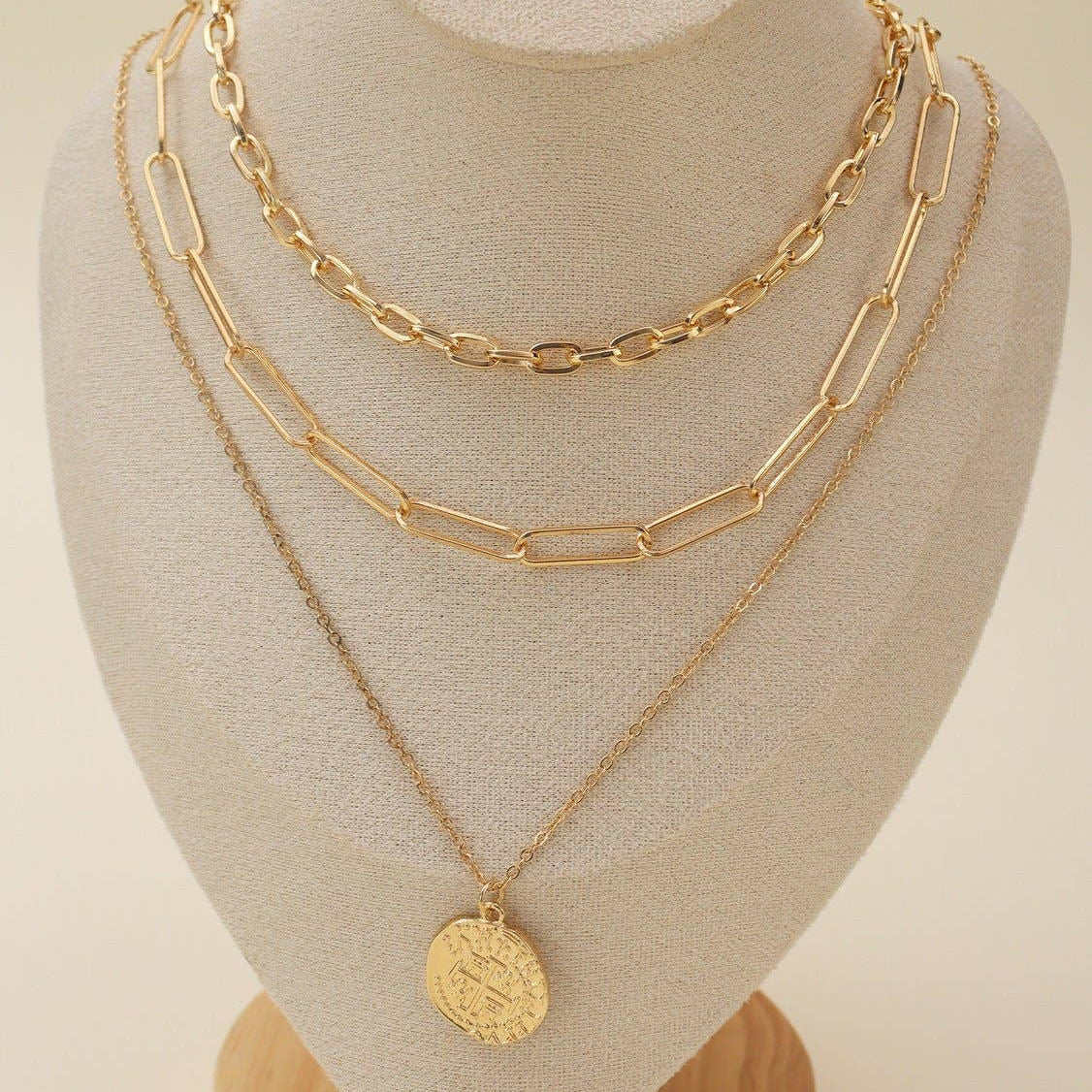 Multi-layer gold chain necklace set showcased on a display bust, featuring delicate pendant and elegant layered design.