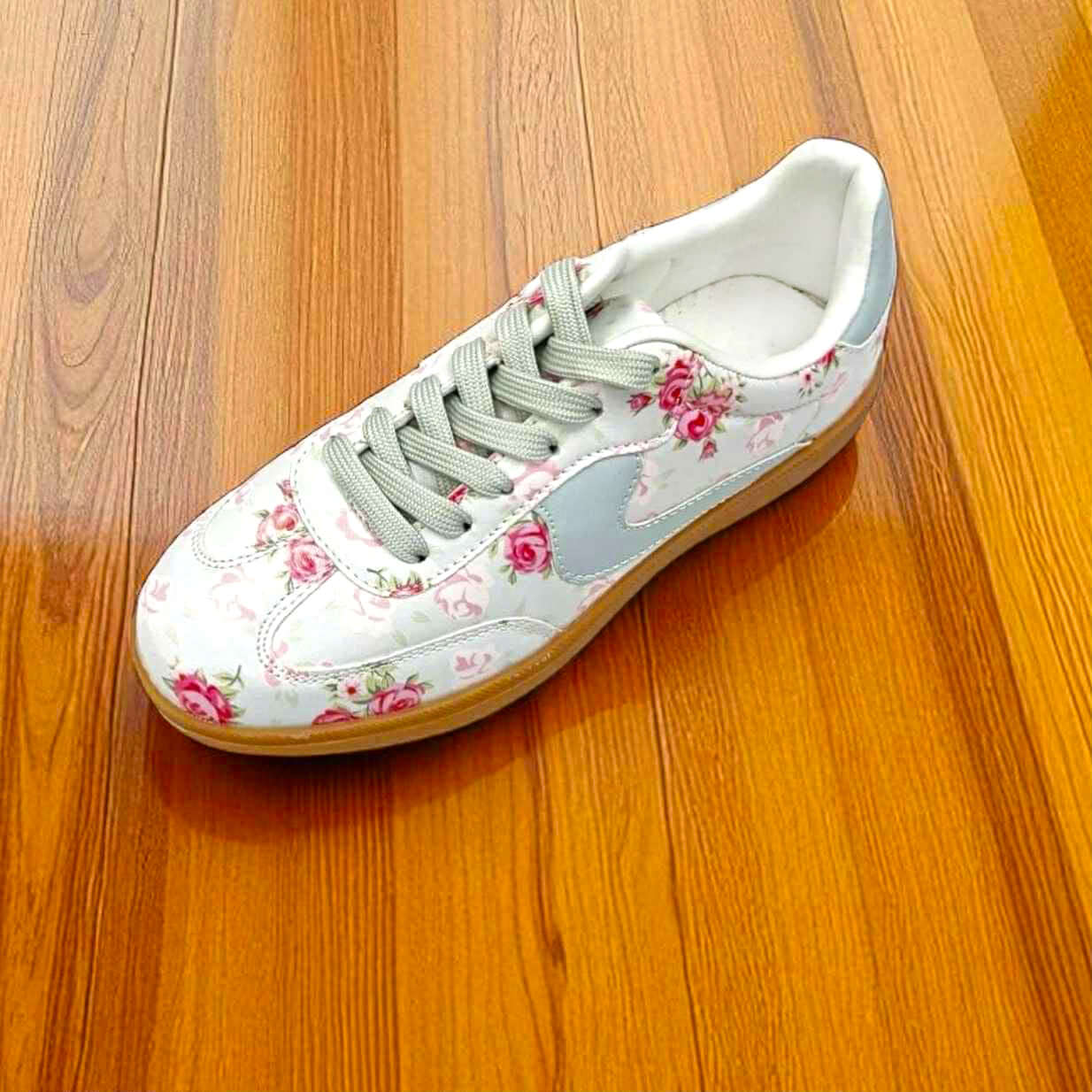 Vintage floral sneakers with mint laces and gum soles on wooden floor.