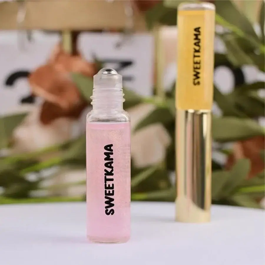 SWEET SCENTS PERFUME ROLLER 2 IN 1 with pink and yellow flacons by SweetKama against green leaves.