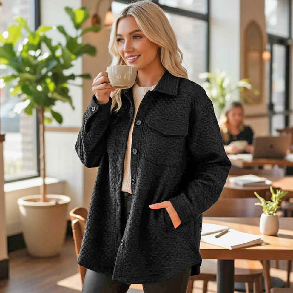 WARM IMPRESSIONS BUTTON DOWN shacket in black worn by a woman enjoying coffee in a stylish cafe.