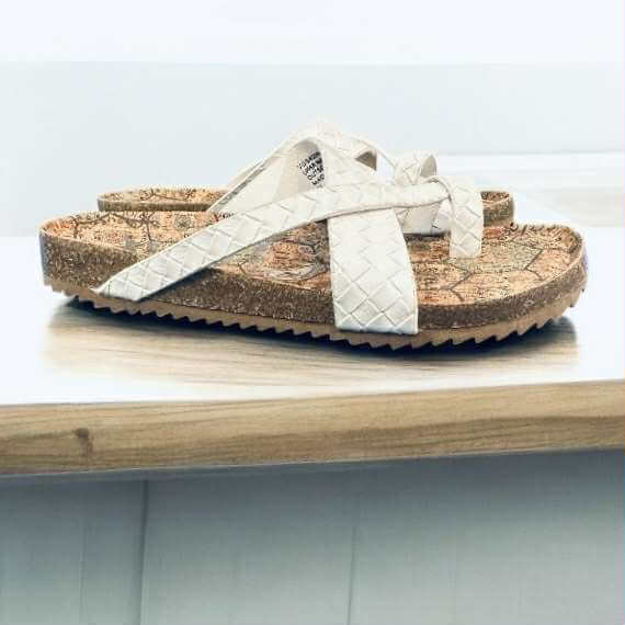 Woven ivory Better Be Me Sandals by Very G on a wooden surface, featuring chic crisscross straps and a toe-loop design.