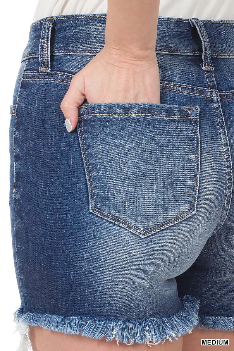 Close-up of Endless Weekend Shorts, mid-rise denim with frayed hem, showing back pocket and medium wash.