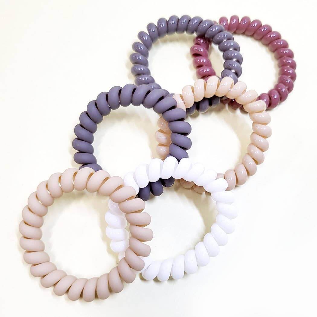 6-piece Twist & Tell hair tie set featuring smooth coil bands in neutral tones and soft pink.