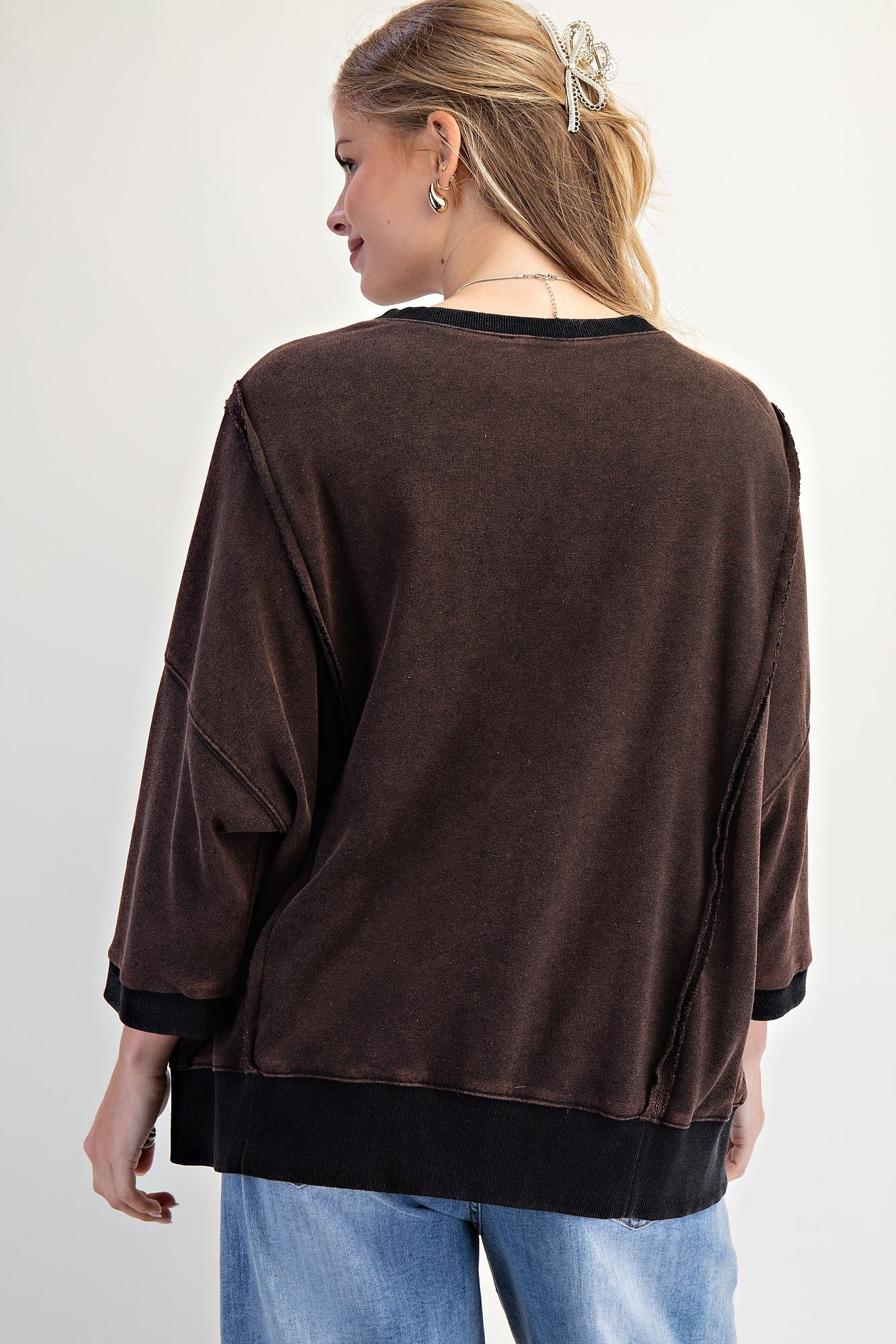 Back view of a woman wearing the LOVE UNTAMED TOP - Easel in dark wash, showcasing its oversized design and comfortable fit.