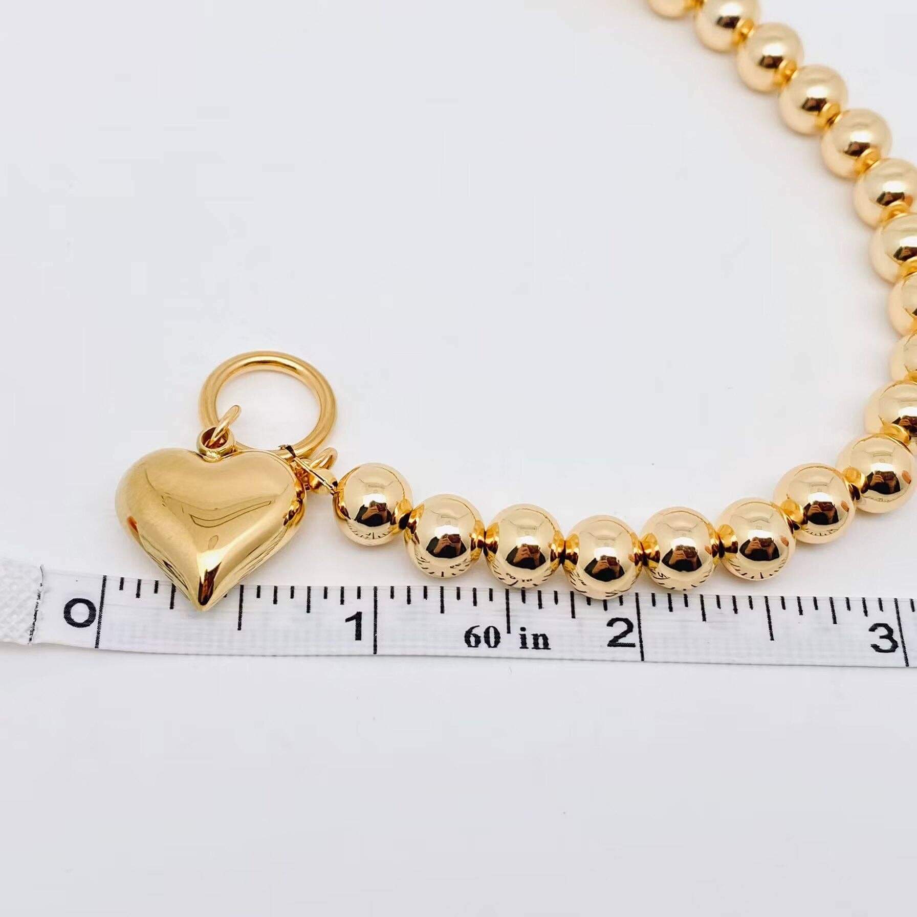 Close-up of the HEART OF GOLD BRACELET featuring glossy gold beads and a polished heart charm.