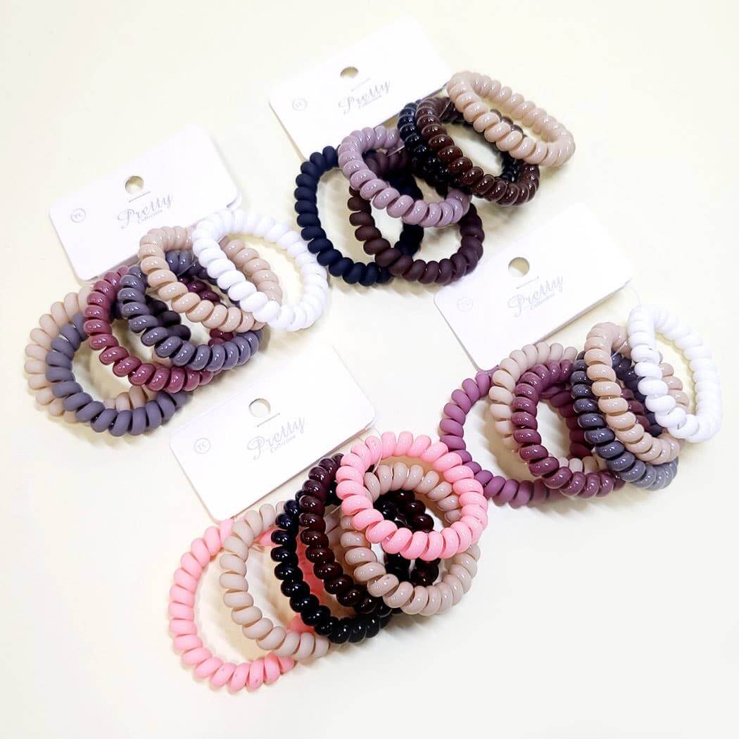 Twist & Tell 6-piece hair tie set with assorted colorful coil bands in neutral and pastel shades.