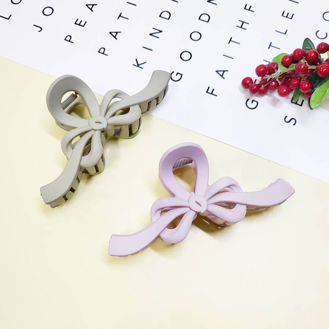 Two matte bow claw clips in sage green and lavender on a pastel background, perfect for stylish hair management.