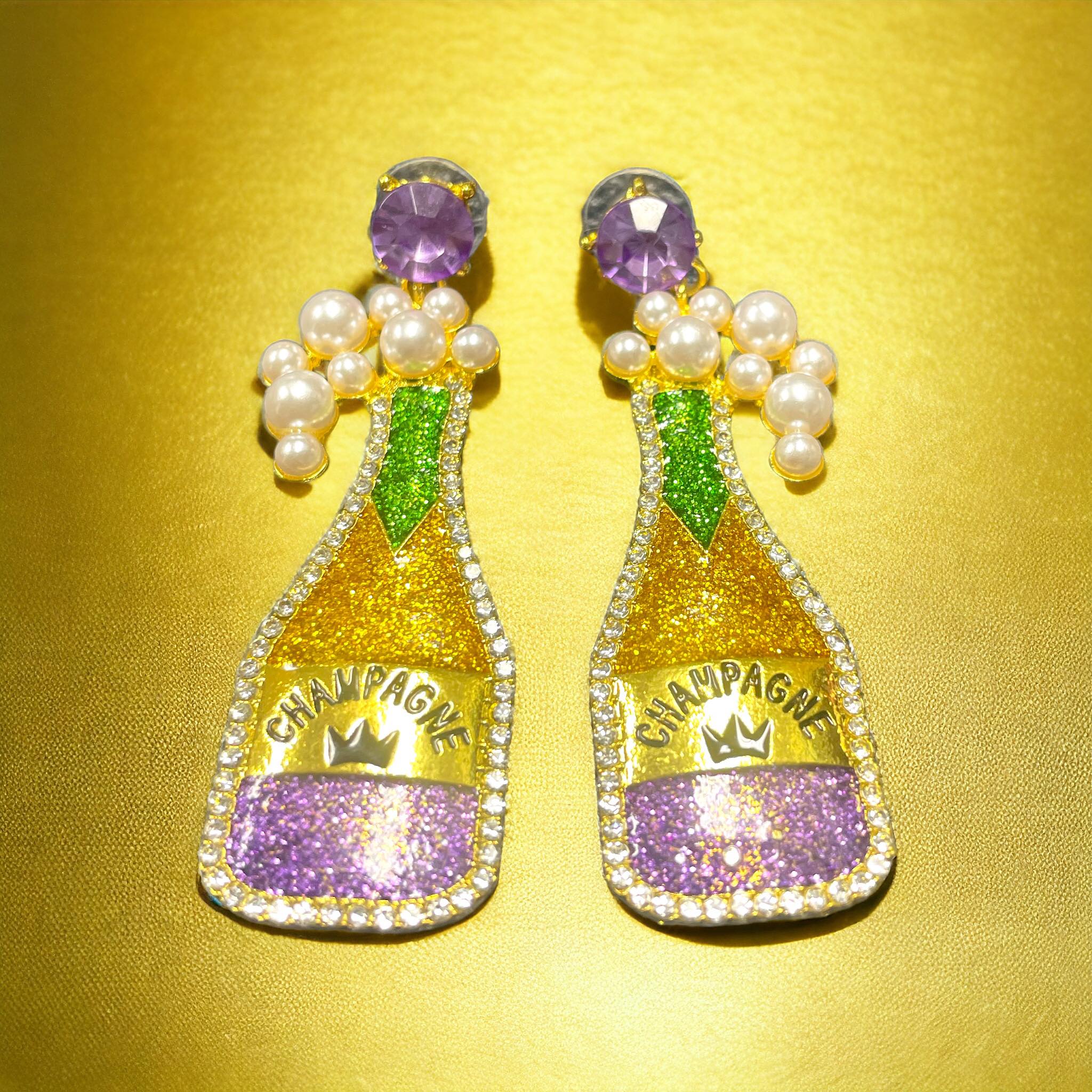 LET THE GOOD TIMES FLOW Earrings with champagne bottle design in purple, gold, and green for festive vibes.