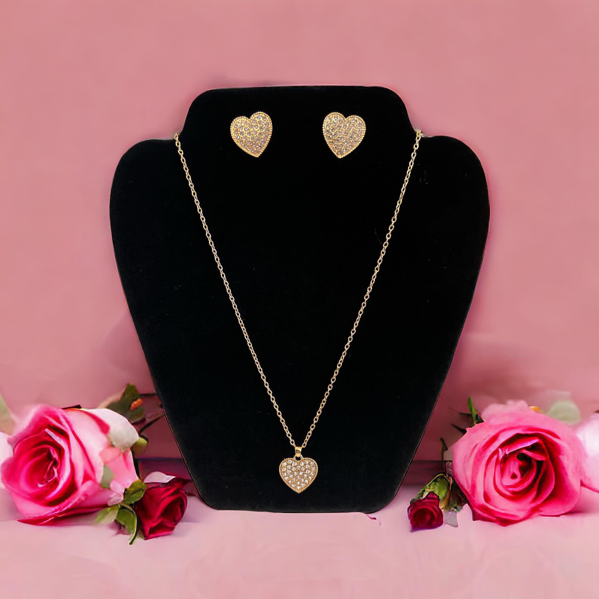 LOVE STORY earrings and necklace set with heart-shaped design in gold tones against a pink background.