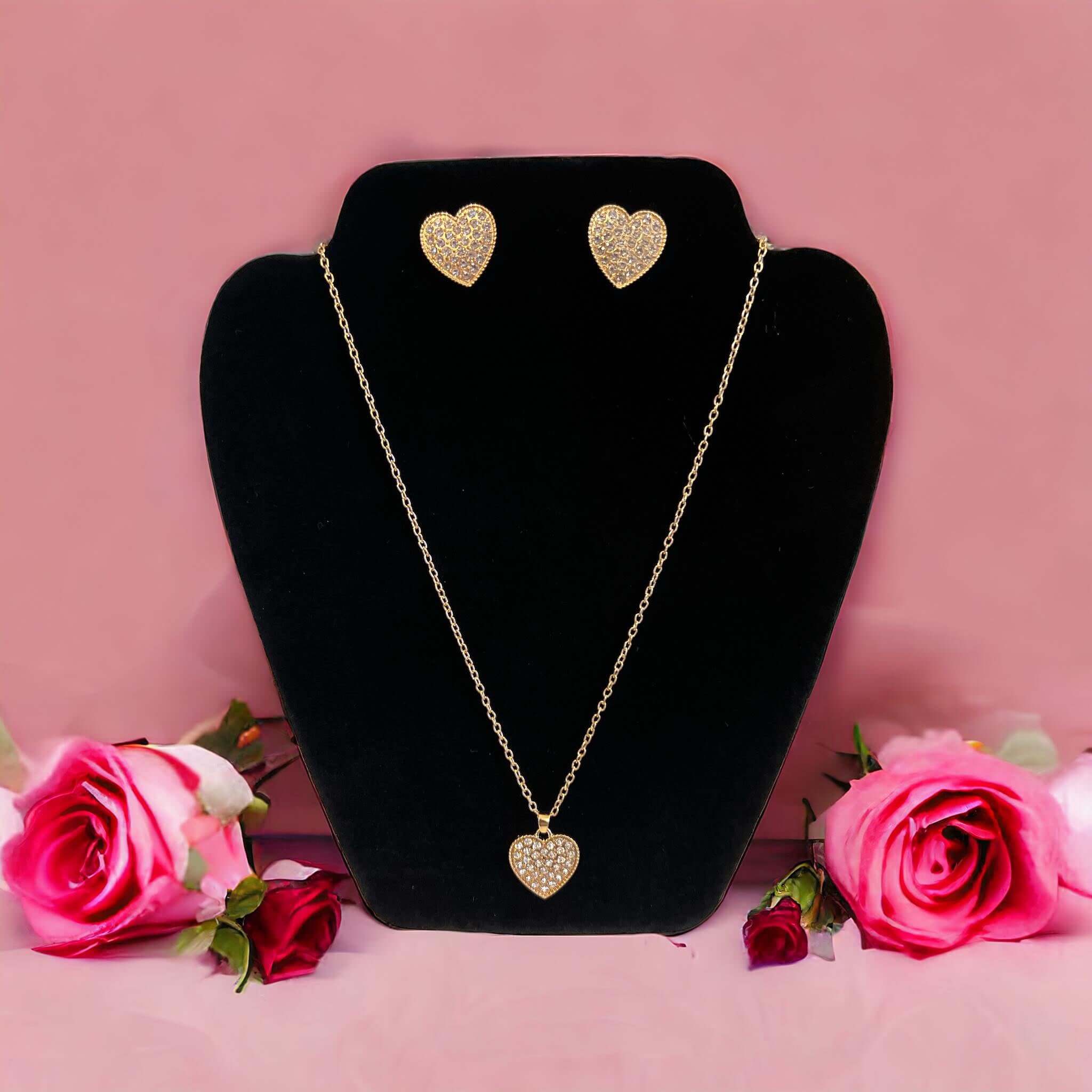 LOVE STORY Earrings and Necklace Set (gold) displayed on a stand with roses, featuring heart-shaped earrings and necklace.