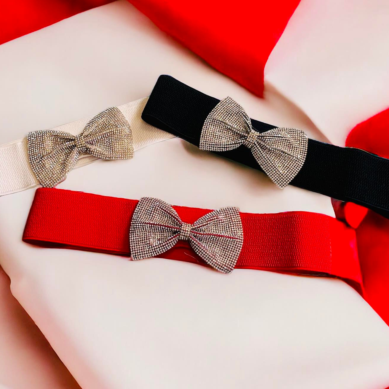 Stylish elastic belts in red, white, and black with rhinestone bows, perfect for adding sparkle to any outfit.