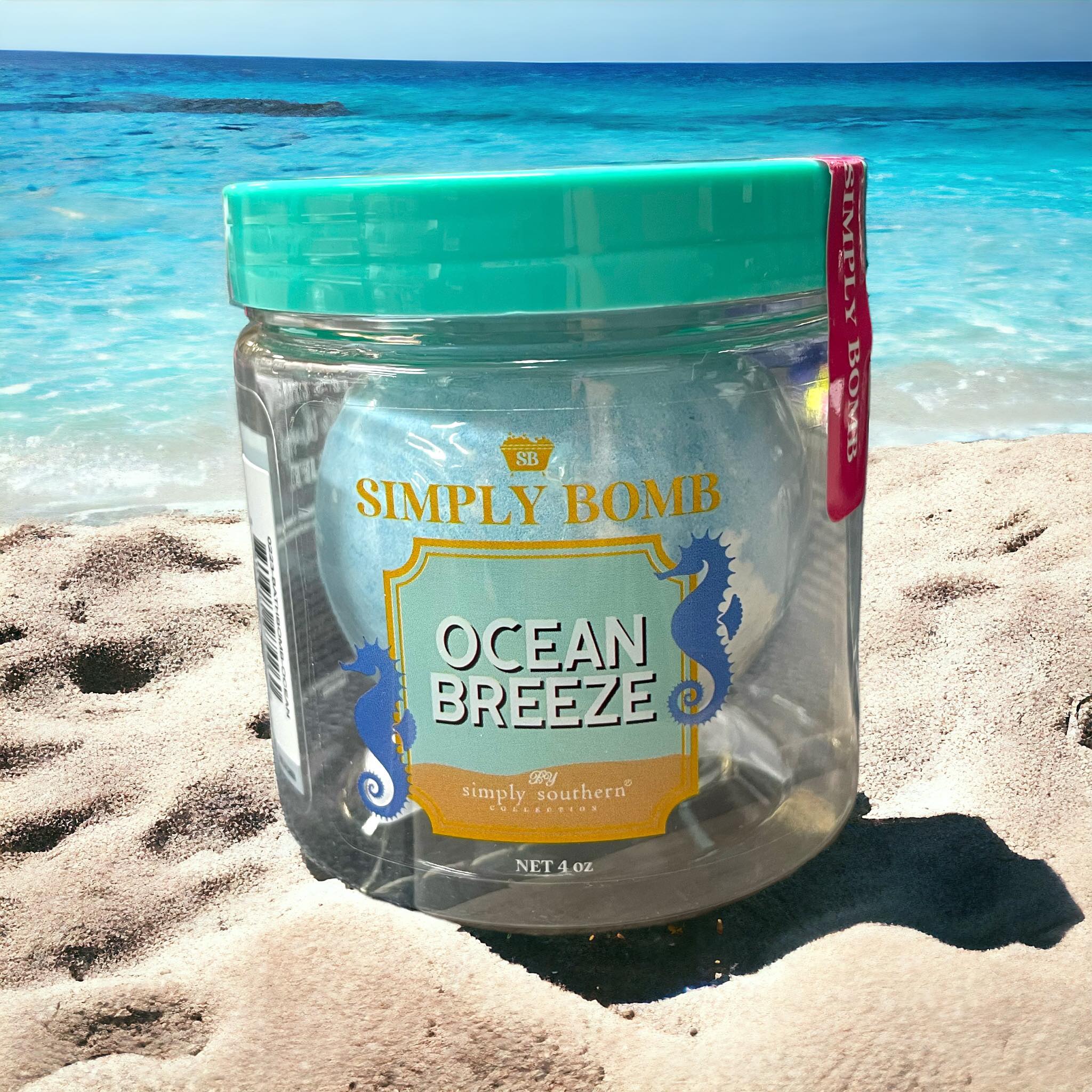 Simply Southern Bath Bombs Ocean Breeze, 4 oz jar on a beach, promoting relaxation and soothing scents.