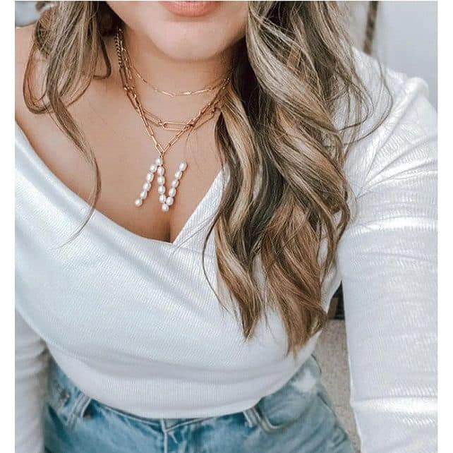 Stylish woman wearing Avenue Zoe's Pearl Essence Monogram Necklace with freshwater pearls on a gold-tone chain.