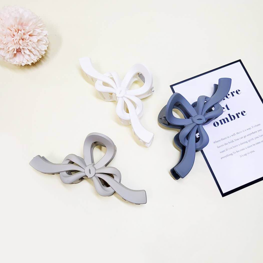 Three Ribbon Revival Hair Clips in gray, white, and blue, showcasing stylish matte bow design.