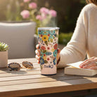 SWIG BELLA ROSA TUMBLR 22 OZ held by a person outdoors with floral design and steam rising, showcasing elegance and functionality.