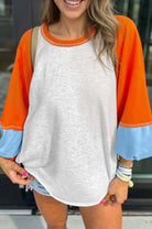 CITRUS CRUSH TOP featuring color block design with tangerine sleeves, sky blue cuffs, and light grey body for versatile style.