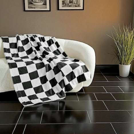 Cozy black-and-white checkerboard nap throw blanket draped over a modern sofa in a stylish living room.