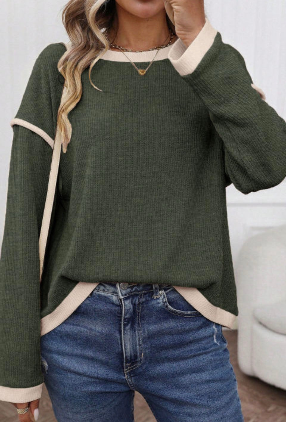 Stylish woman wearing EARTHLINE ENERGY TOP in green with beige accents and casual blue jeans.