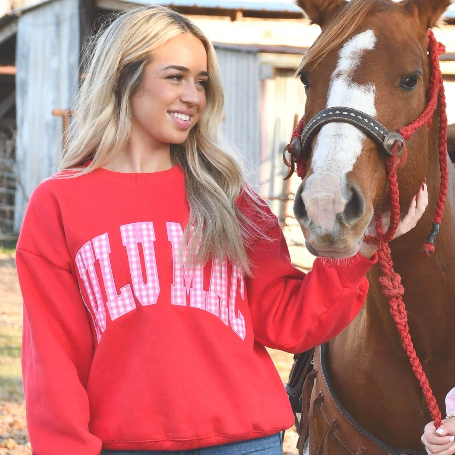LULU MAC RED W/PINK GINGHAM CREWNECK worn by a woman standing beside a horse, showcasing Southern charm and style.
