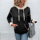 Woman wearing a MODERN EDGE HOODIE with contrast seams, paired with jeans and a stylish handbag for a casual look.