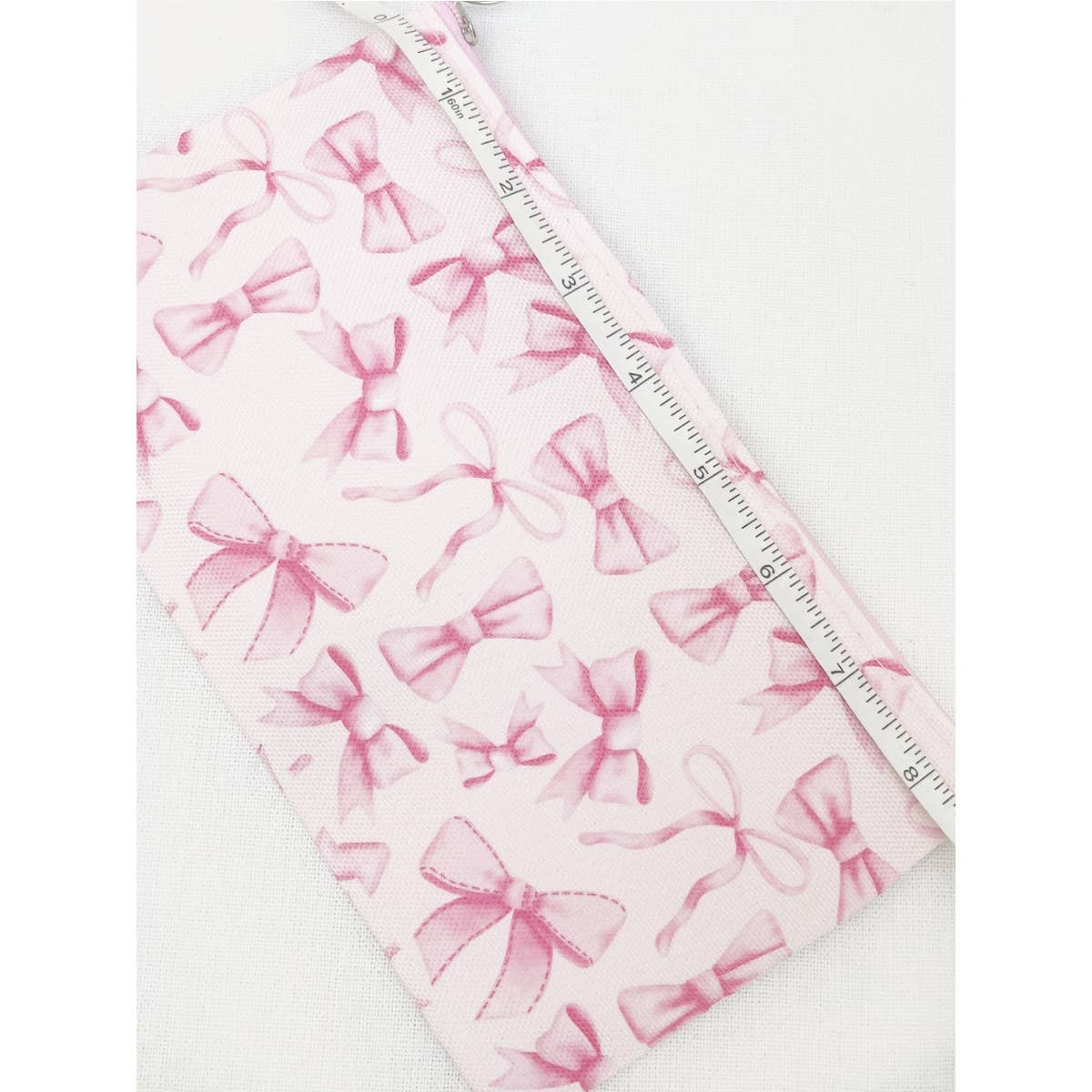 BOW ME OVER COSMETICS BAG in pink with stylish bow design, measuring 8.5 x 5 inches, perfect for organizing makeup essentials.