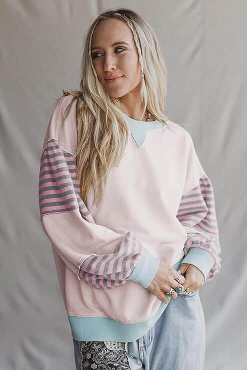 Woman wearing EASYGOING ERA CREW (taffy) with striped patchwork sleeves and a relaxed fit.