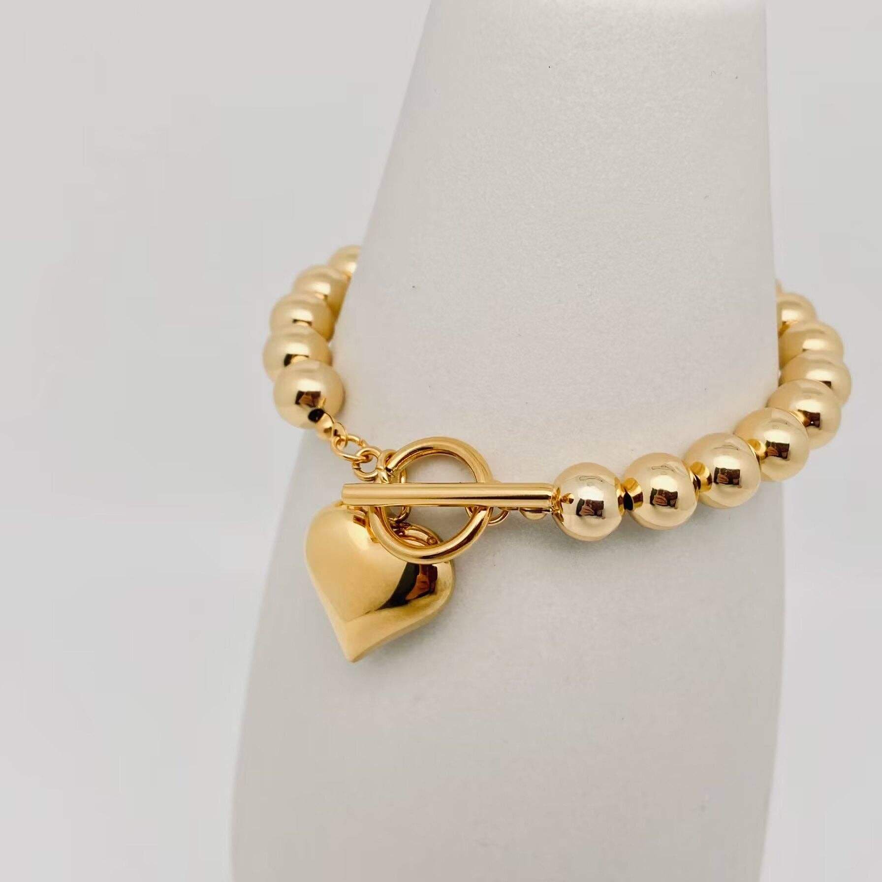 HEART OF GOLD BRACELET featuring glossy gold beads and polished heart charm on a elegant display.