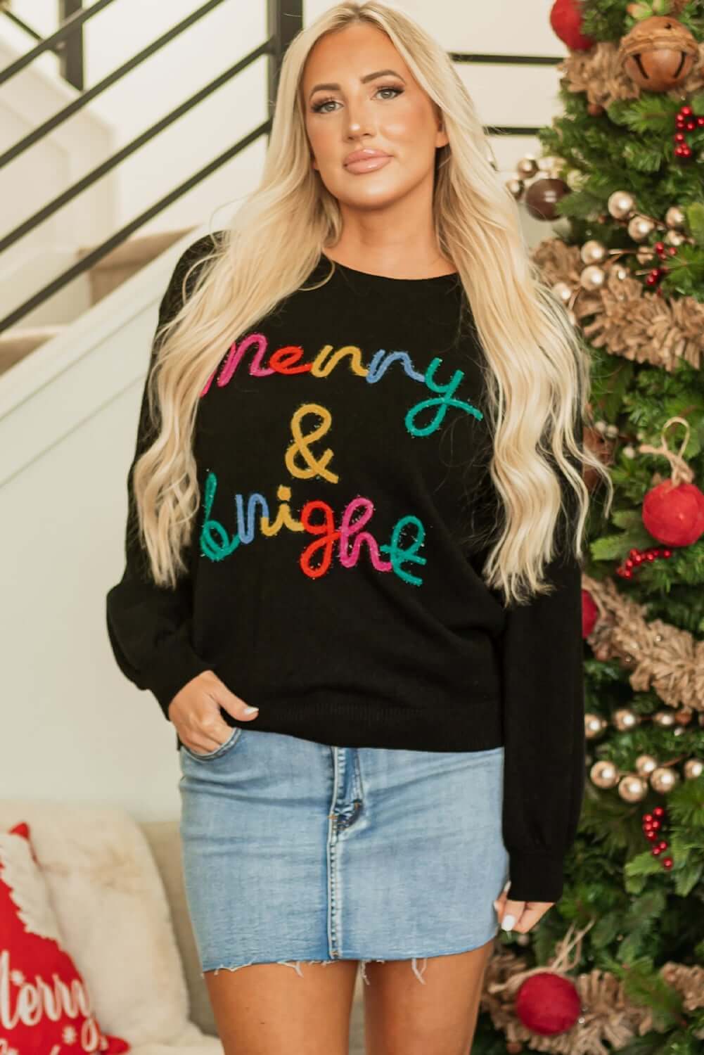 Merry & Bright sweater by Vivian-Lu on model, featuring colorful tinsel letters in a festive black design.