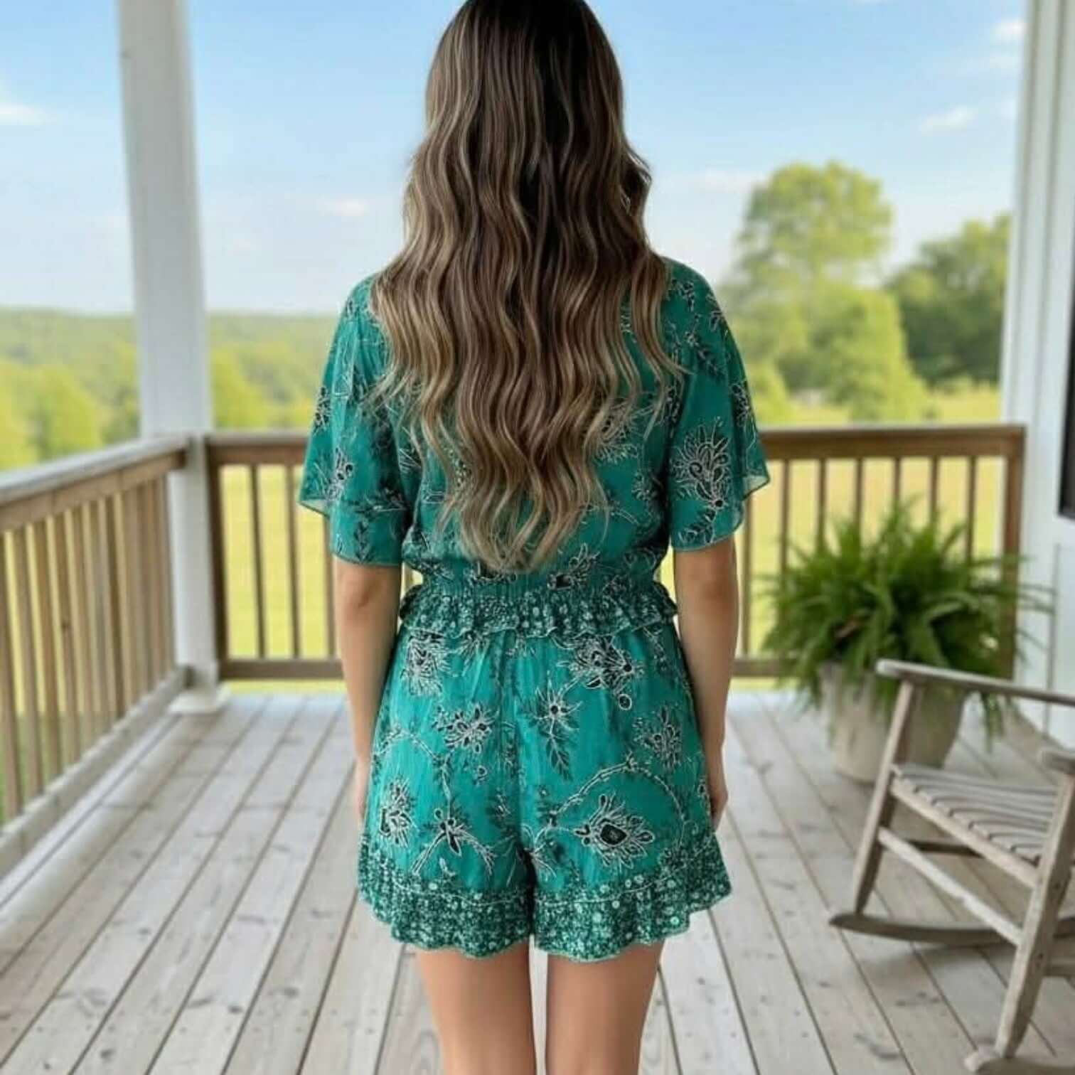 Back view of a woman wearing a CHARMED IM SURE ROMPER - Gigio, showcasing its stylish design and vibrant color.