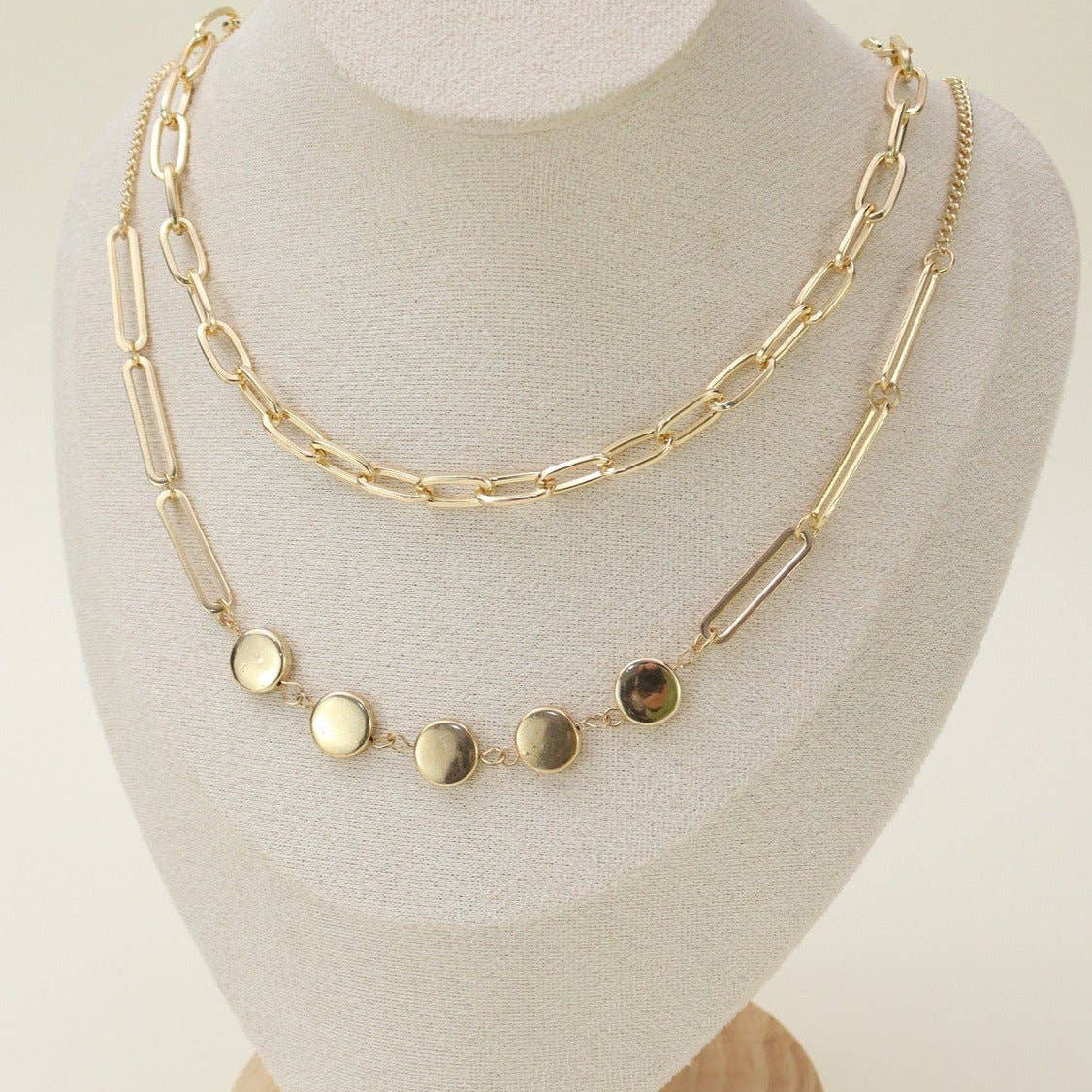 Two Layer Chain Necklace Set displayed on a stand, featuring elegant gold chains and circular accents for versatile styling.