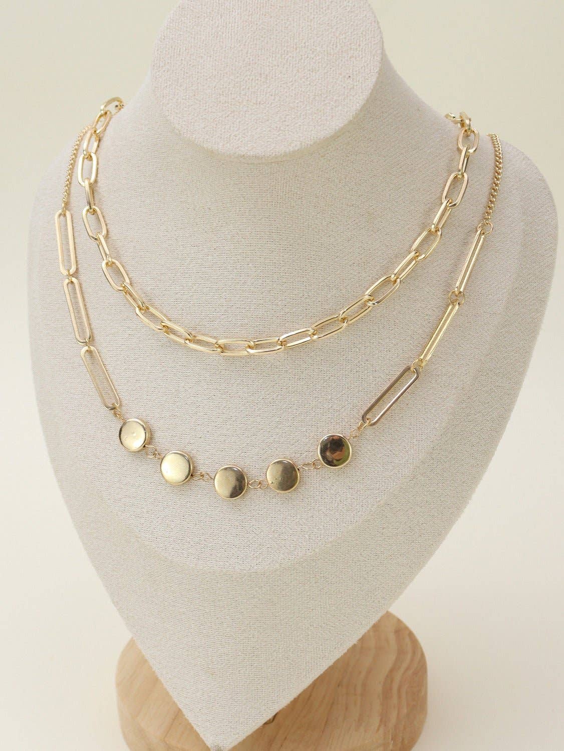 Two Layer Chain Necklace Set displayed on a stand, featuring elegant gold chains and circular accents for versatile styling.