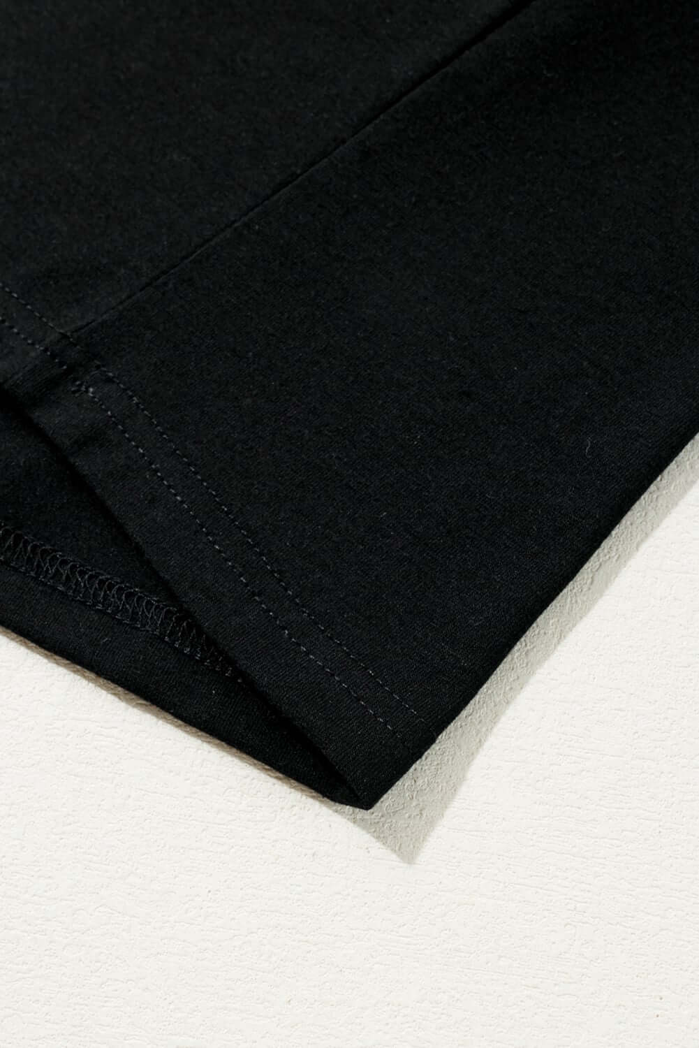 Close-up of black t-shirt hem showcasing soft fabric and stitching detail, perfect for stylish Christmas wear.