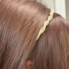 Close-up of a pearl embellished hairband on brown hair, adding elegance and sophistication to a holiday look.