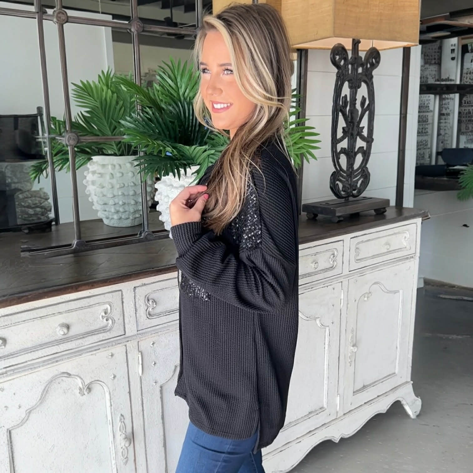 Model wearing CITY LIGHTS TOP, a black sequin patch corded shacket, styled with cozy comfort in a modern setting.