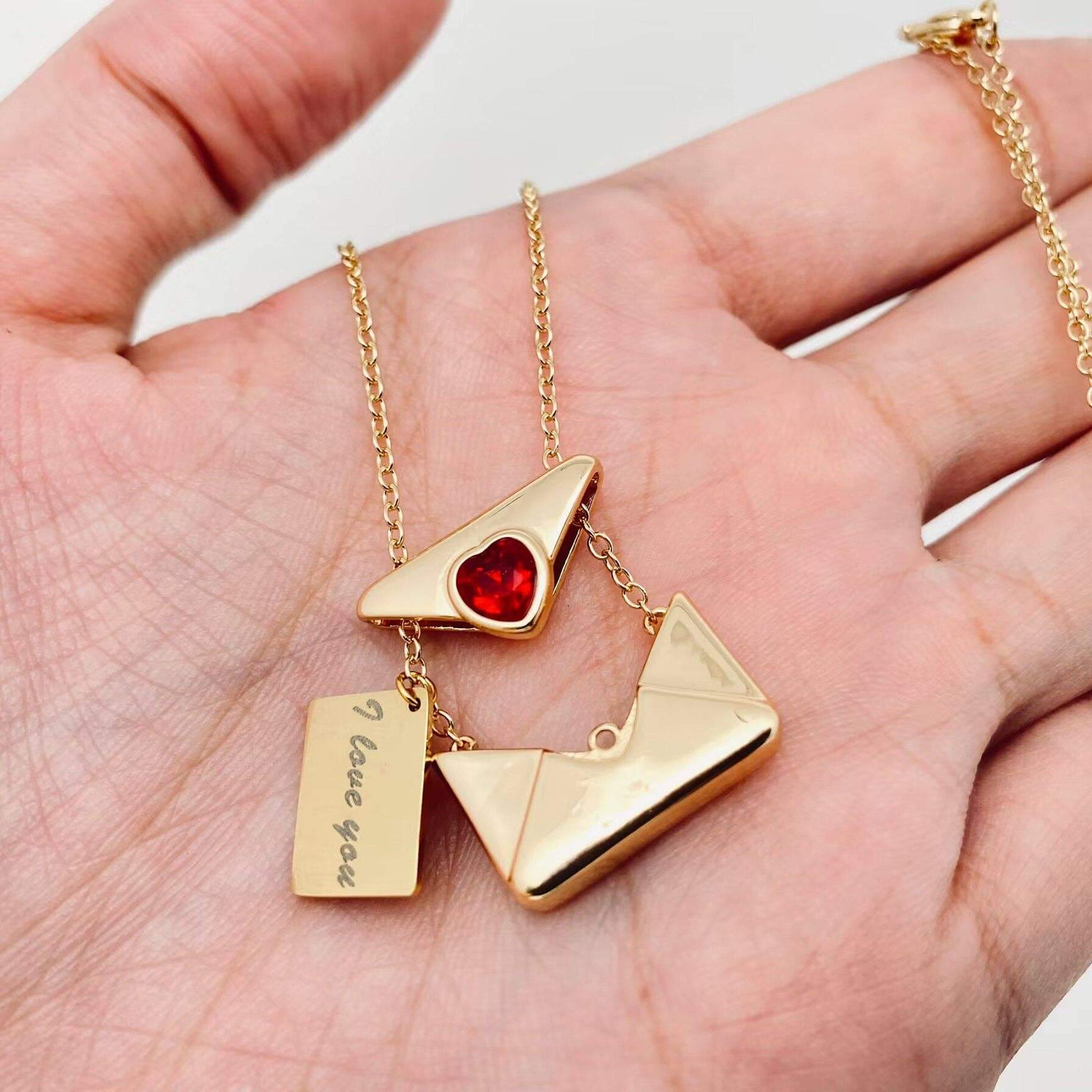 LOVE LETTER NECKLACE featuring a gold pendant with a heart and a charm that says 'I love you' on a delicate chain.