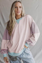 A model wearing the EASYGOING ERA CREW (taffy) sweatshirt featuring colorblock design and striped sleeves.