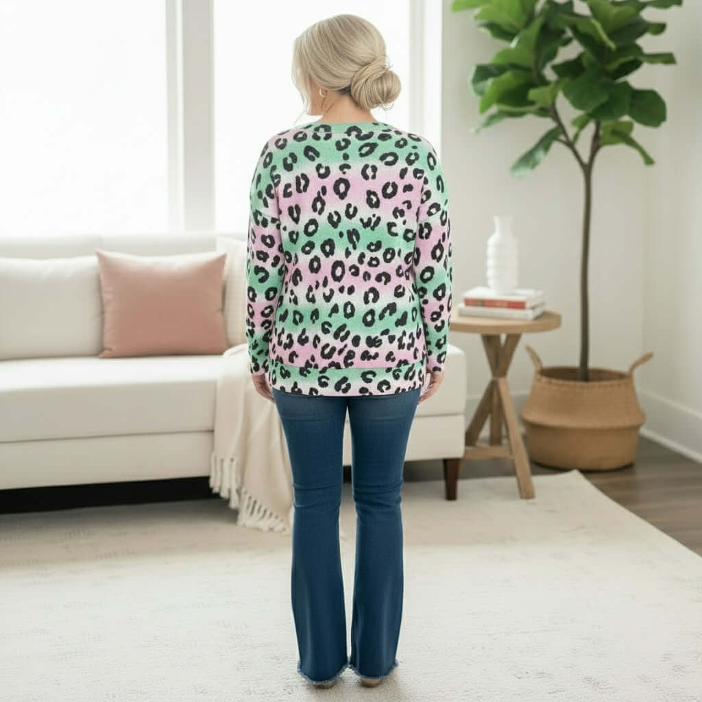 Back view of a woman wearing the PRETTY PROWL TOP - Zenana with playful leopard print and relaxed fit, styled with flared jeans.