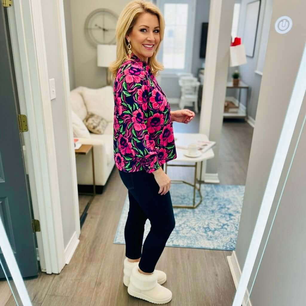 Model wearing the SIENNA LOVESTRUCK TOP by Michelle McDowell with vibrant floral print, paired with navy leggings and cozy boots.