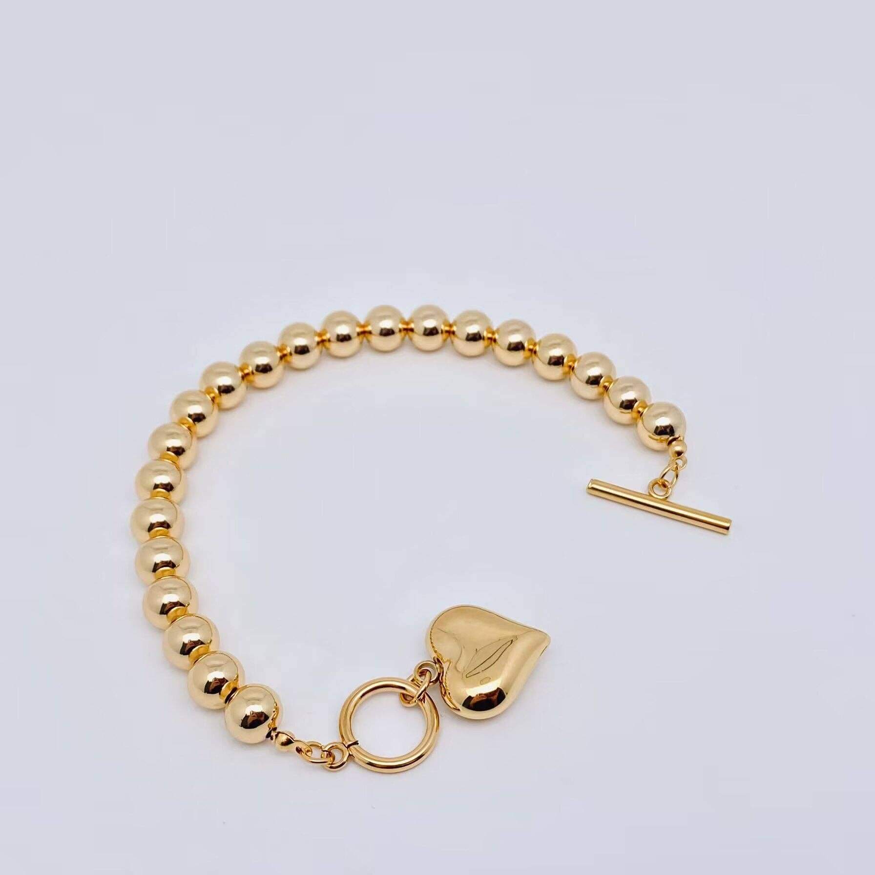 HEART OF GOLD BRACELET featuring glossy gold beads and polished heart charm with toggle closure.