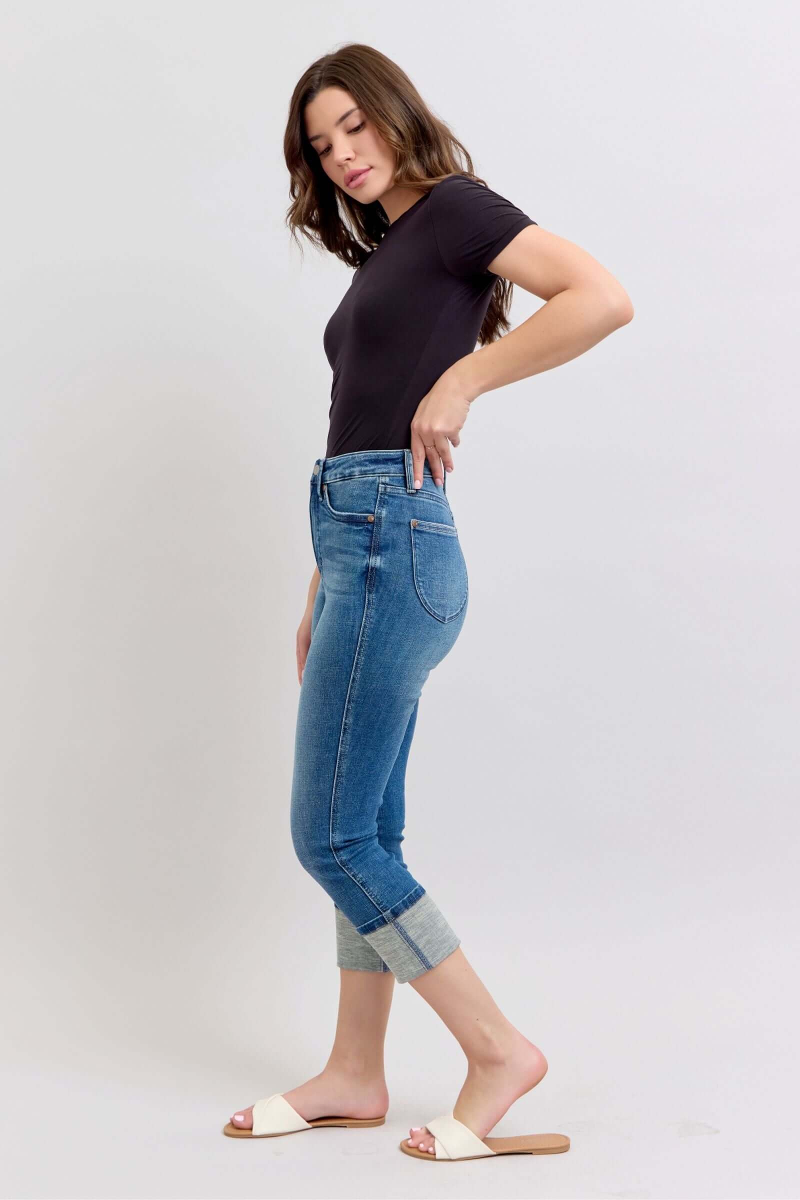 Model showcasing JUDY BLUE Charli Capris in medium wash, high waist with cuffed hem, emphasizing tummy control feature.