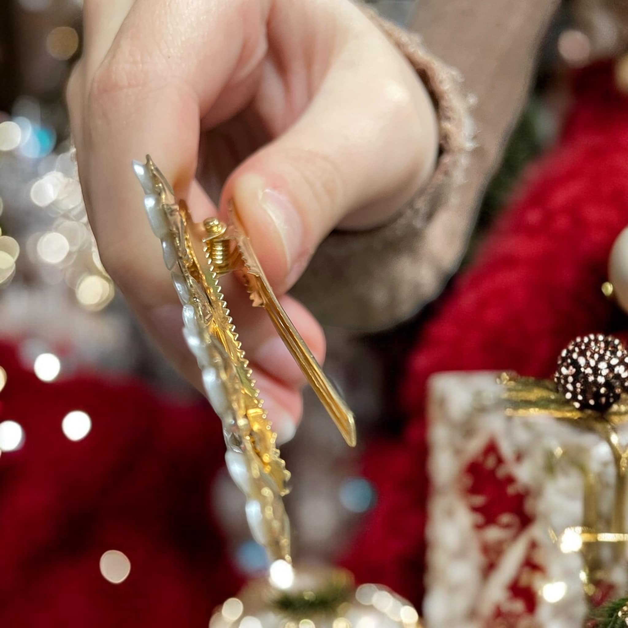 Close-up of a hand holding a gold rhinestone hair clip, showcasing its intricate design and elegant details.