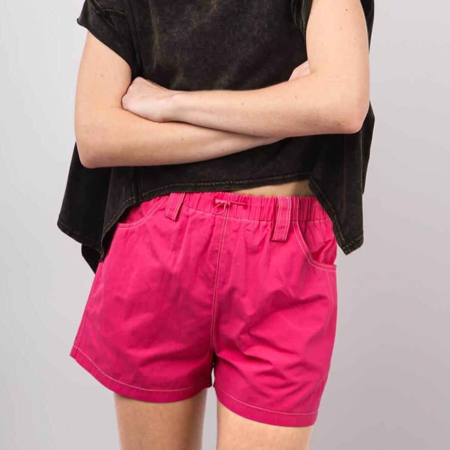 Model wearing hot pink Play It Cool Shorts with a relaxed fit and black crop top against a neutral background.