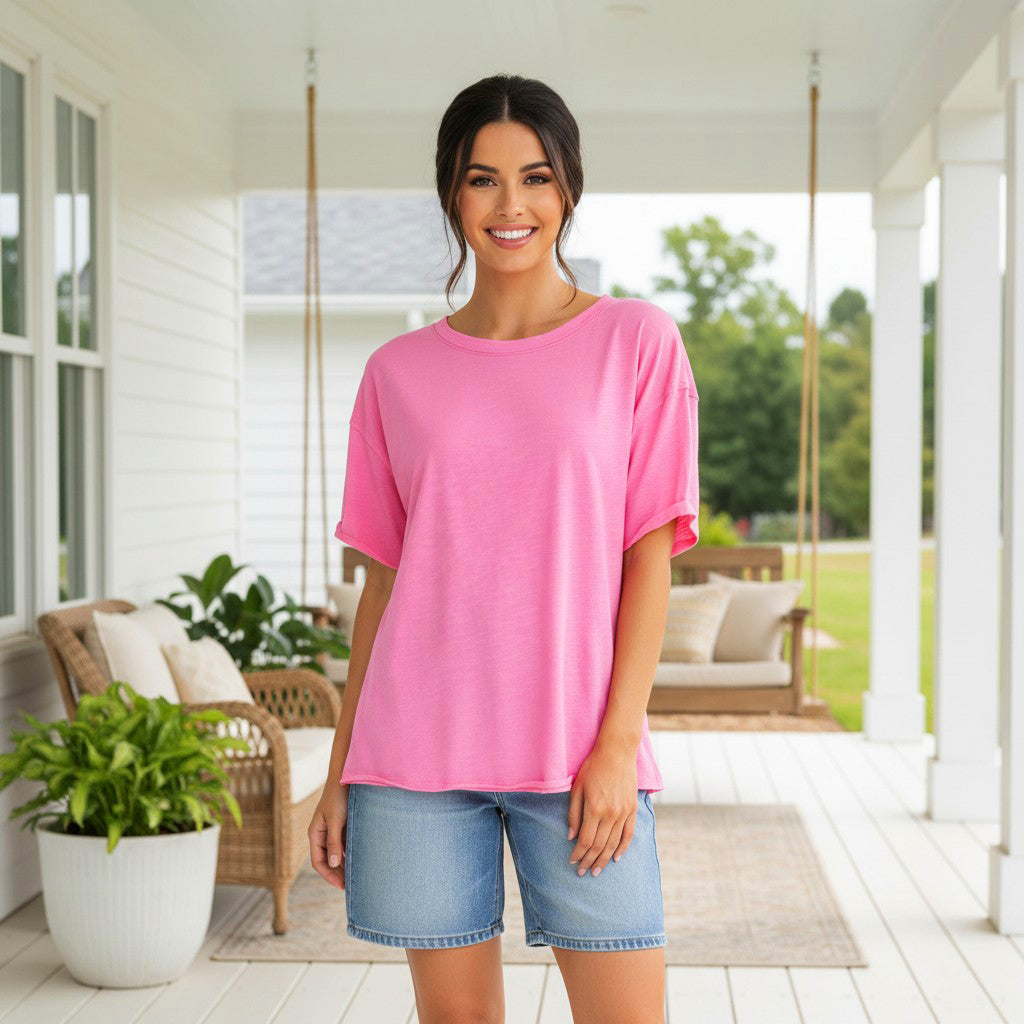 Woman wearing FEEL GOOD FAVE TOP - Andree' (pink) with shorts, standing on a porch with greenery.
