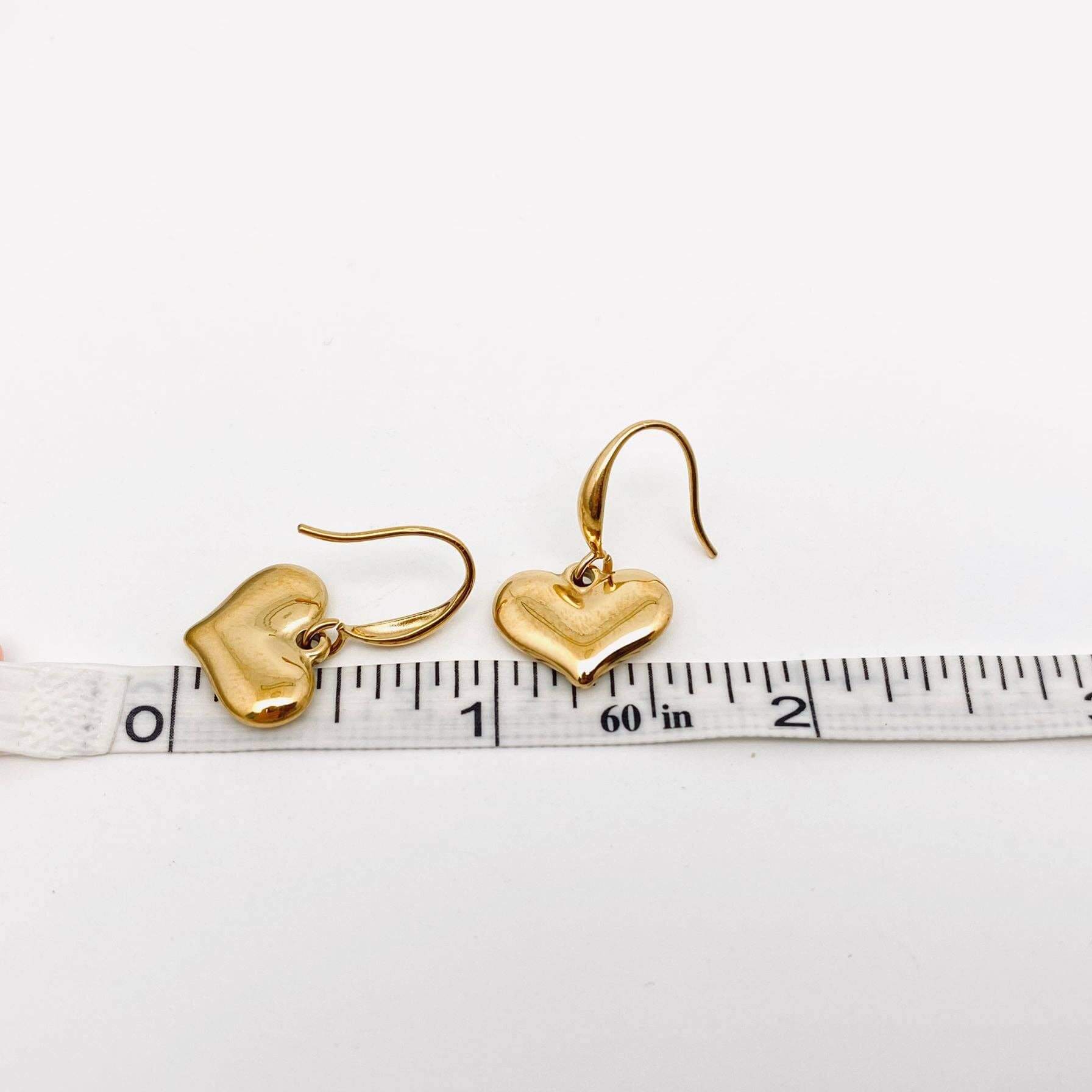 Forever Yours Earrings showcased with a ruler, featuring polished gold heart drops for a romantic touch.