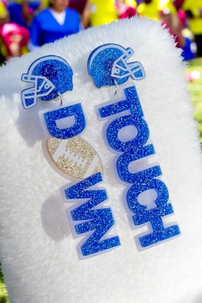 Score Touch Down earrings featuring blue glitter helmets and bold letters, perfect for football fans on game day.